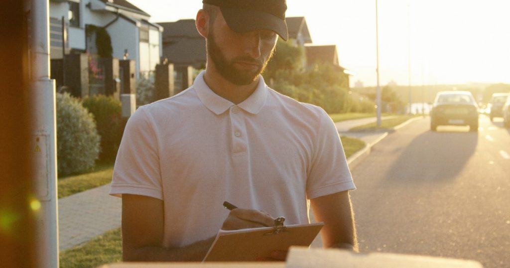 Man looks over delivery boxes while checking packaging slips.